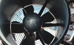 Exaustor axial e centrífugo industrial visto de perto, destacando suas pás e estrutura metálica — exemplo prático na diferença entre exaustores axiais e centrífugos.