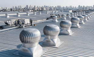 Exaustores eólicos instalados no telhado de um galpão industrial para exaustão industrial e economia de energia.